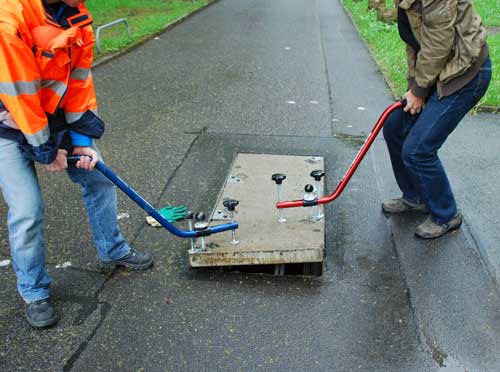 Schachtdeckel wird zu zweit ausgehoben